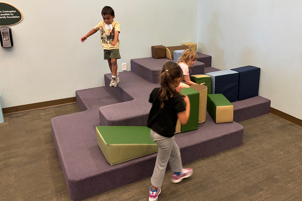 Children climb and play on soft indoor blocks, building balance and coordination.
